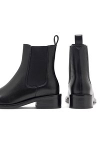 Musthave nahkased Chelsea saapad elastsete külgpaneelidega, ümarate varvaste ja madalate blokknäppudega; siledat tekstuuri ja tõmblukkudega mugavaks jalga panemiseks.