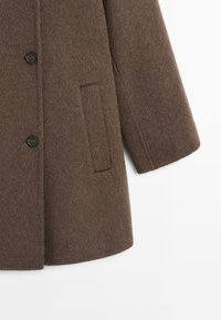 Cappotto di lana marrone con una silhouette rilassata, tre bottoni neri e una tasca laterale, con una finitura morbida e testurizzata.