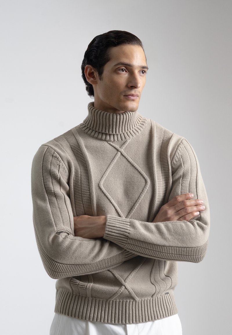 Suéter de cuello alto beige con textura acanalada, patrón de tejido de diamante y mangas ajustadas. Presenta un cuello alto y un ajuste ceñido.