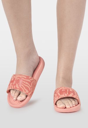 Pies con sandalias tipo slide de color coral con tiras estampadas y letras "HH" en relieve en la parte superior, mostrados sobre un fondo claro y uniforme.