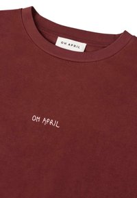 Burgundská bavlněná tričko s kulatým výstřihem a malým logem "OH APRIL" vyšitým růžovou barvou na přední straně. Měkká textura a uvolněný střih.