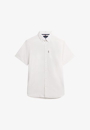 Chemise blanche à manches courtes, à col, avec une poche poitrine et une texture subtile. Caractérisée par une couleur unie sans motifs visibles.