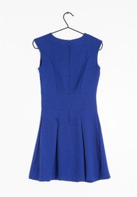 Robe sans manches en tissu texturé bleu roi, corsage ajusté, jupe évasée et fermeture éclair dans le dos. Suspendue à un crochet noir.