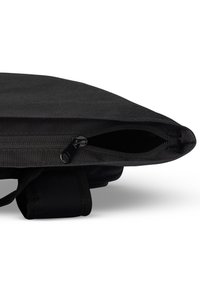 Svart tygväska med zip-förslutning, med texturerat material och robusta bärhandtag. Ren design med minimalistisk struktur.
