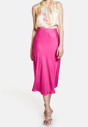 Damesoutfit met een mouwloze, zijden top met bloemenpatroon en een mid-lange, felroze satijnen rok, gecombineerd met beige sandalen met bandjes.