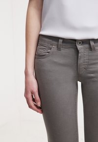 Grå denim jeans med en smal passform, subtila fickdetaljer, knapplist och dragkedja, samt en mjuk textur.