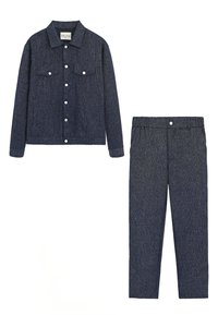 Veste en denim foncé avec deux poches poitrine et fermeture à boutons, associée à un pantalon à taille élastique assorti. Les deux pièces présentent un tissu texturé.