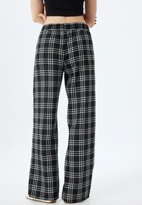 Pantalons larges à carreaux noir et blanc avec une taille élastique, fabriqués dans un tissu doux et offrant une coupe décontractée.