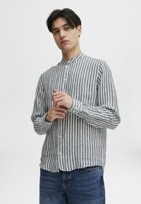 Camisa de botones a rayas en azul claro y blanco, fabricada con una tela texturizada, con cuello de banda y manga larga.
