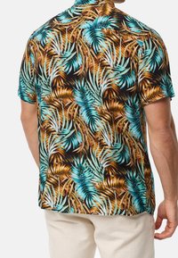 Lyhytsleeve-paita, jossa on trooppinen palmulehtikuvio teal, ruskeana ja mustana. Valmistettu kevyestä kankaasta, jossa on rento istuvuus.