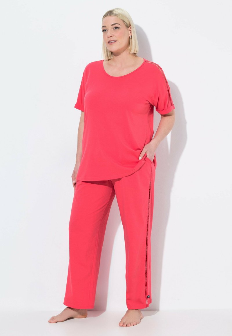 Roze lounge-outfit bestaande uit een T-shirt met korte mouwen en bijpassende broek met zijaccenten. Zachte stof, losse pasvorm en comfortabel ontwerp.
