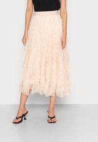 Jupe à volants couleur pêche avec un design en couches et une large ceinture. Le tissu semble léger et transparent, créant une silhouette fluide.