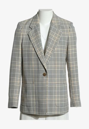 Veste à carreaux grise à un bouton avec des accents beiges, revers crantés et poches avant sur un buste de mannequin blanc.