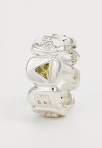 Hõbedane sõrmus, millel on ümarad ristkülikukujulised segmendid, millel on graveeritud sümbolid ja keskel kollane kolmnurkne vääriskivi.