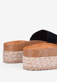 Sandali con piattaforma nera e base in sughero, con intersuola in juta intrecciata e una soletta marrone liscia. Tacco elevato con suole texturizzate.