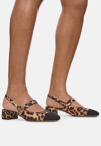 Leopard-print slingback shoes with a black toe cap, block heel, and cross strap details. Made of sleek fabric with a smooth texture.