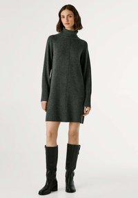 Abito maglione grigio scuro a collo alto, con polsini e orlo a costine; design al ginocchio completato da stivali neri alti.