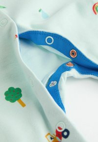 Body in cotone azzurro chiaro con stampe colorate di alberi, gocce di pioggia e veicoli, dotato di bottoni a pressione blu e dettagli in rame.