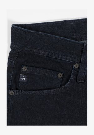 Mørke denimjeans med rette ben, med en liten frontlomme, metallknapper og en logotag på midjen.
