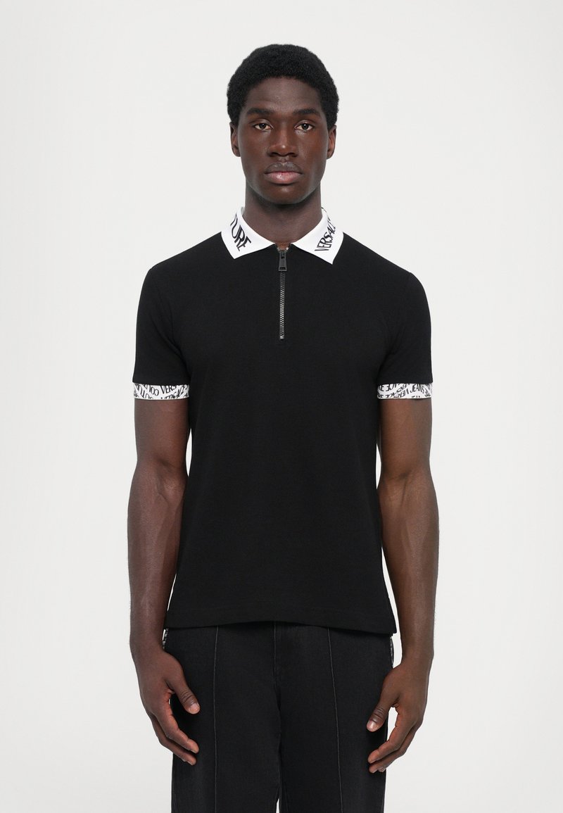 Camisola polo preta com colarinho com fecho, detalhe em logo branco no colarinho e nas mangas, e design ajustado. Tecido suave com mangas curtas.