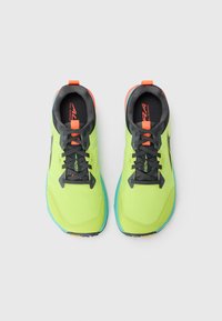 Chaussures de trail running vert vif et noires avec semelles bleues et accents orange, vues de dessus sur un fond blanc.