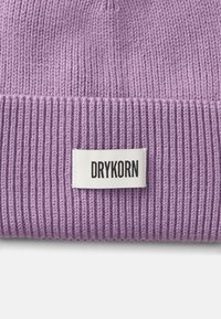Touca de malha canelada roxa com aba dobrada, apresentando uma etiqueta branca com o rótulo "DRYKORN" para marca. Textura suave.