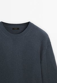 Granatowy sweter z okrągłym dekoltem, z prążkowanymi mankietami i dołem. Wykonany z teksturowanej tkaniny z miękkim, dzianinowym wykończeniem.