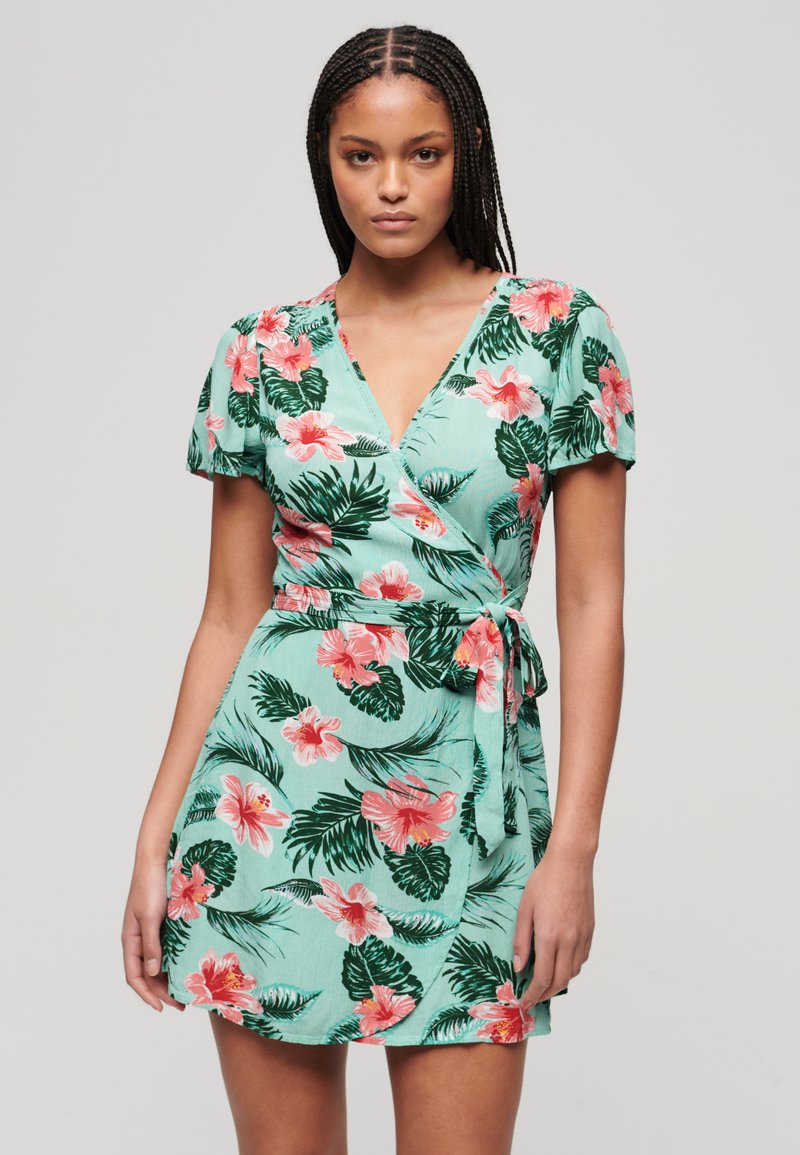 Bloemen wikkeljurk in lichtgroen met roze hibiscus en groene bladeren patronen. Korte pofmouwen en een striksluiting in de taille.