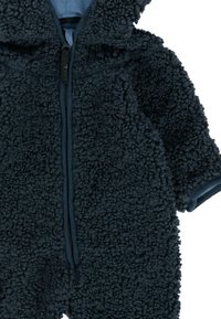 Donkerblauwe, fuzzy sneeuwpak gemaakt van gestructureerde stof, met een lange rits en een capuchon, met contrasterende blauwe voering.