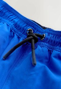 Niebieskie spodenki kąpielowe z czarnym sznurkiem, elastycznym pasem i gładką fakturą materiału. Z wzmocnionymi szwami i detalem z logo.