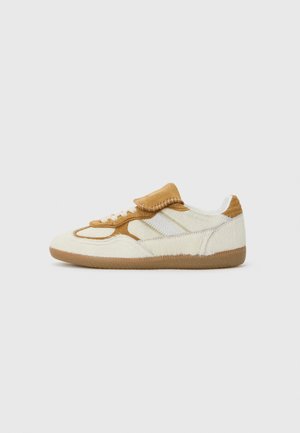 Sneaker with white textured leather and tan suede accents, featuring a round toe, laces, and a padded tongue. Rubber sole with brown detailing.