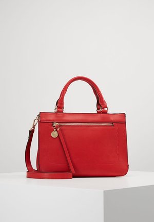 Czerwona skórzana torebka z dwoma uchwytami i odpinanym paskiem na ramię, z przednią kieszenią na suwak z zamkiem w złotym odcieniu i ozdobą.