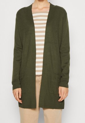 Olijfgroene cardigan met een geribbelde textuur; open voorkant, lange mouwen en twee voorzakken. Gestreept shirt eronder.