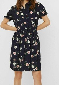 Blumenkleid aus dunkelblauem Stoff mit kurzen Puffärmeln, einer Knopfleiste vorne, einem elastischen Taillenbund und einem Muster aus rosa und weißen Blumen.