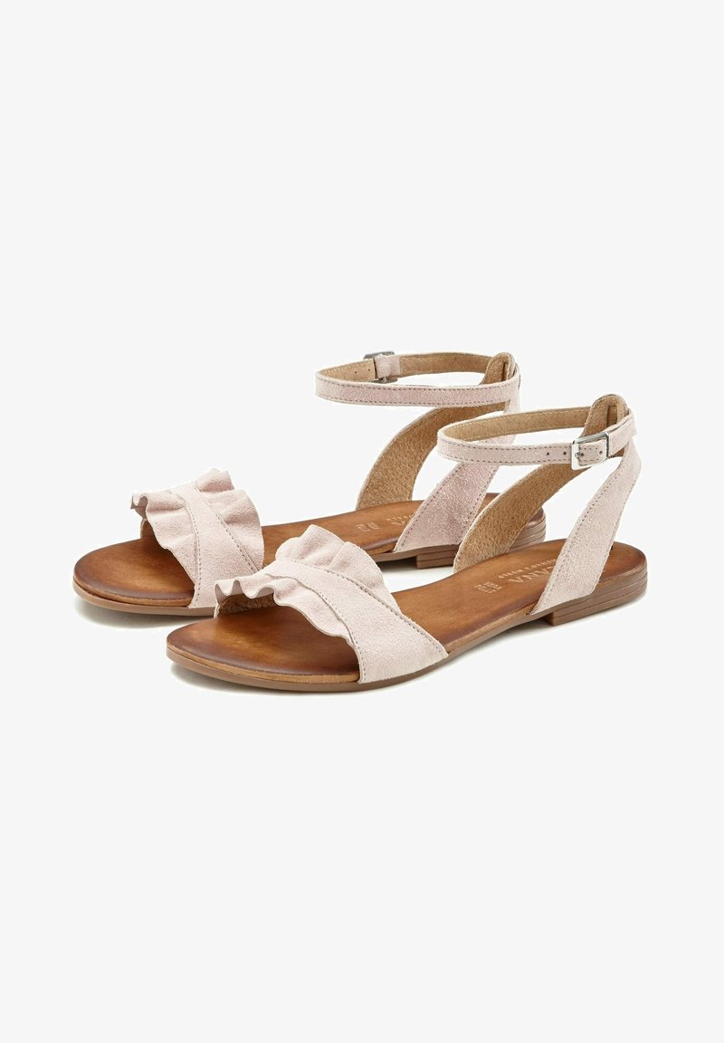 Sandales en daim rose clair avec avant à volants, semelle plate en bois et deux brides de cheville ajustables. Design simple, à bout ouvert.
