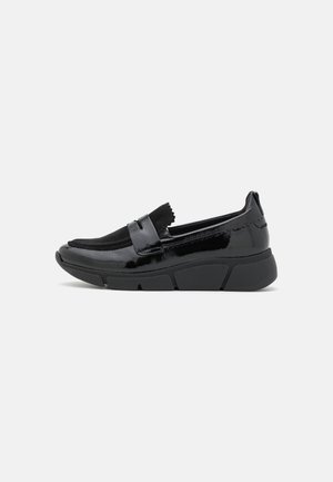 Sort laklæder slip-on loafer med chunky sål og ruskindsoverdel, sidevisning på ensartet lys baggrund.