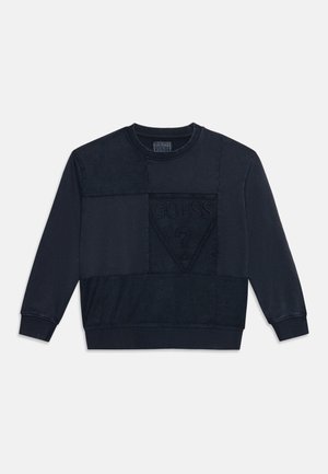 Sweat-shirt noir à col rond avec manches longues et design patchwork, orné d'un logo Guess embossé en forme de triangle sur la poitrine.