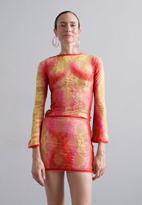 Long-sleeve, sheer top and mini skirt set in a vibrant gradient of yellow, pink, and red with a floral lace pattern and contrast trim.