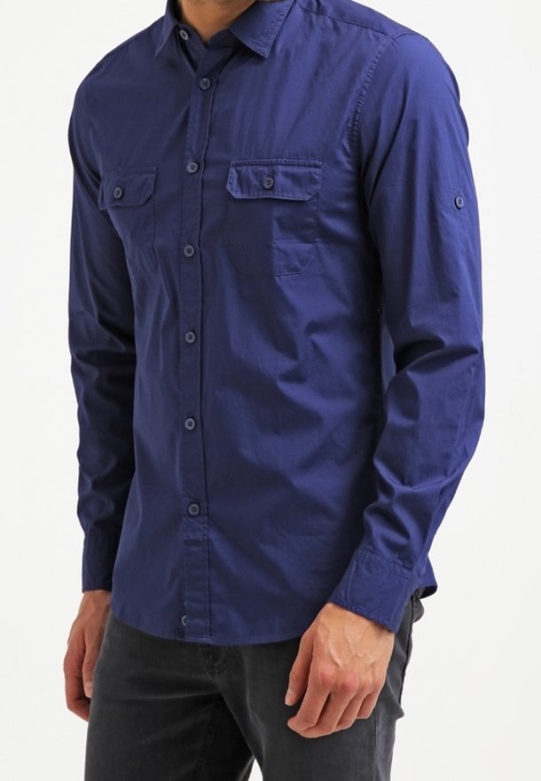 Mörkblå långärmad skjorta i bomull med knappad krage, två bröstfickor och knäppte ärmslut.