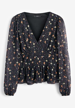 Blouse noire à manches longues avec un petit imprimé floral orange, crème et violet, col en V profond, taille froncée et manches bouffantes légèrement transparentes.