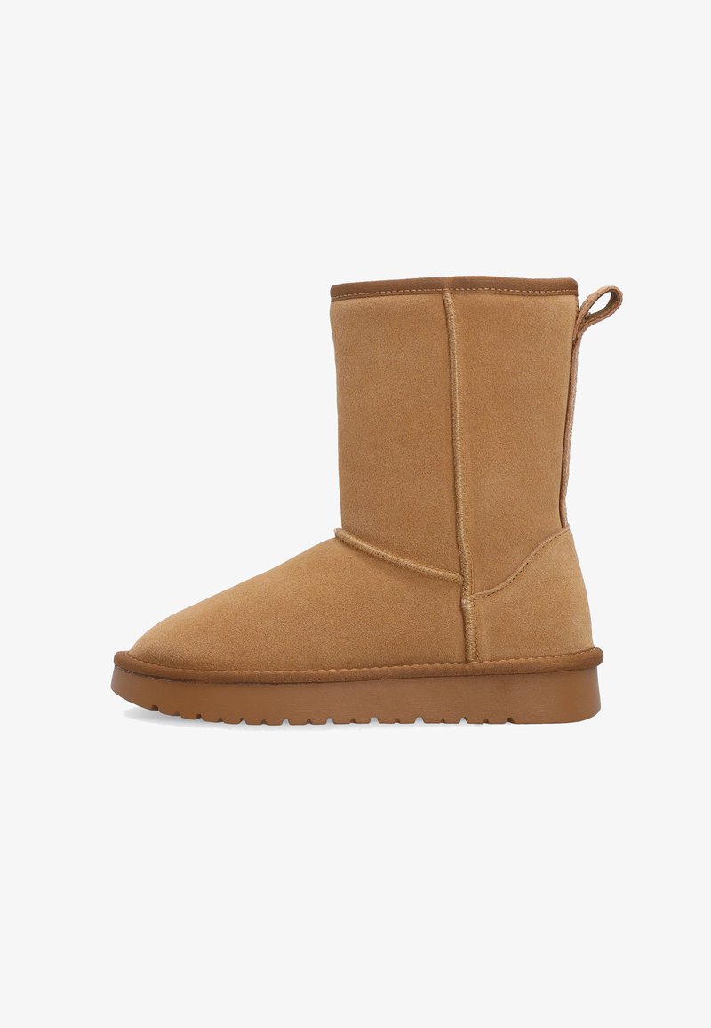 Beżowy zamszowy botek za kostkę z zaokrąglonym czubkiem, płaską gumową podeszwą i detalami szwów. Krótki fason z pętlą z tyłu ułatwiającą zakładanie.