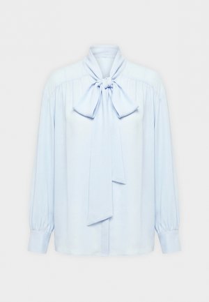 Hele sinine pika varrukaga pluus, millel on kogutud õlad, laiad mansetid ja suur seotud lips kaelal.