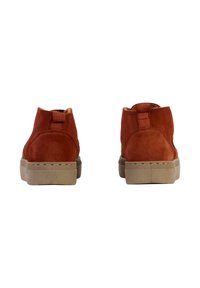 Bottes chelsea en suède marron avec un bout rond, une tige courte et une semelle en caoutchouc beige. Présente un tirant à l'arrière et des coutures en zigzag.