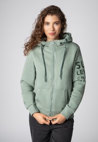 Lichtgroene rits hoodie met een trekkoordkap, voorzakken en bedrukt tekst op de mouw. Soepele stof, casual pasvorm, ribgebreide boorden.