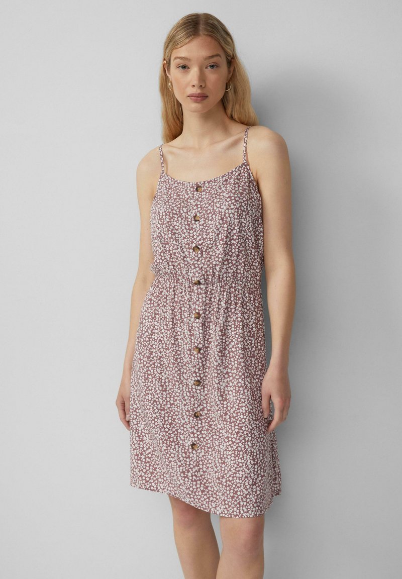 Kleid mit floralen Mustern in hellrosa mit kleinen weißen Blumen, verstellbaren Spaghettiträgern, gerafftem Taillenbereich und Frontknopfverschluss.