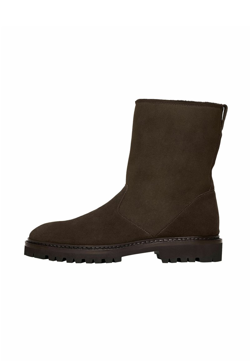 Bota de ante marrón hasta el tobillo con puntera redonda, textura suave, tirador y suela de goma resistente. Diseño sencillo sin patrones visibles ni herrajes.