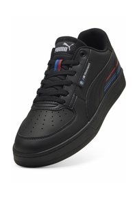 Adidași negri din piele, cu vârful perforat, șireturi negre și logo-ul Puma. Prezintă dungi roșii și albastre cu brandingul BMW Motorsport.