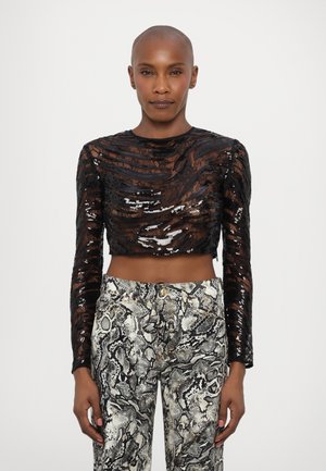 Black, long-sleeve, cropped top featuring textured sequins in waves. Paired with fitted pants displaying a monochrome snake print pattern.