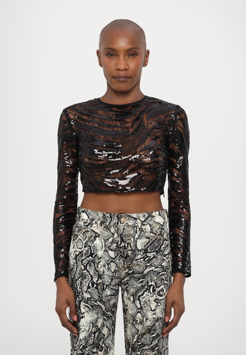 Fekete, hosszú ujjas, cropped top, ami hullámos domború paillettes-szel díszített. Fitted nadrággal párosítva, amely monokróm kígyómintás mintázattal rendelkezik.