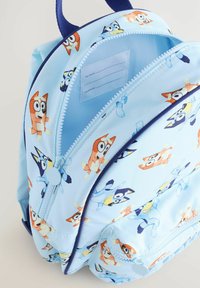 Világoskék hátizsák rajzfilm kutya mintákkal, cipzáras záródással, belső név- és telefonszámlabellel. Tartós anyag texturált felülettel.